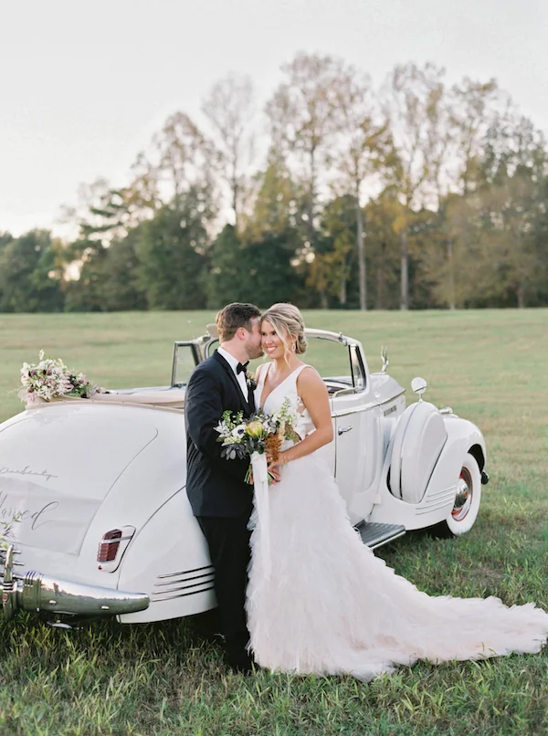 Bride and groom beside a vintage car