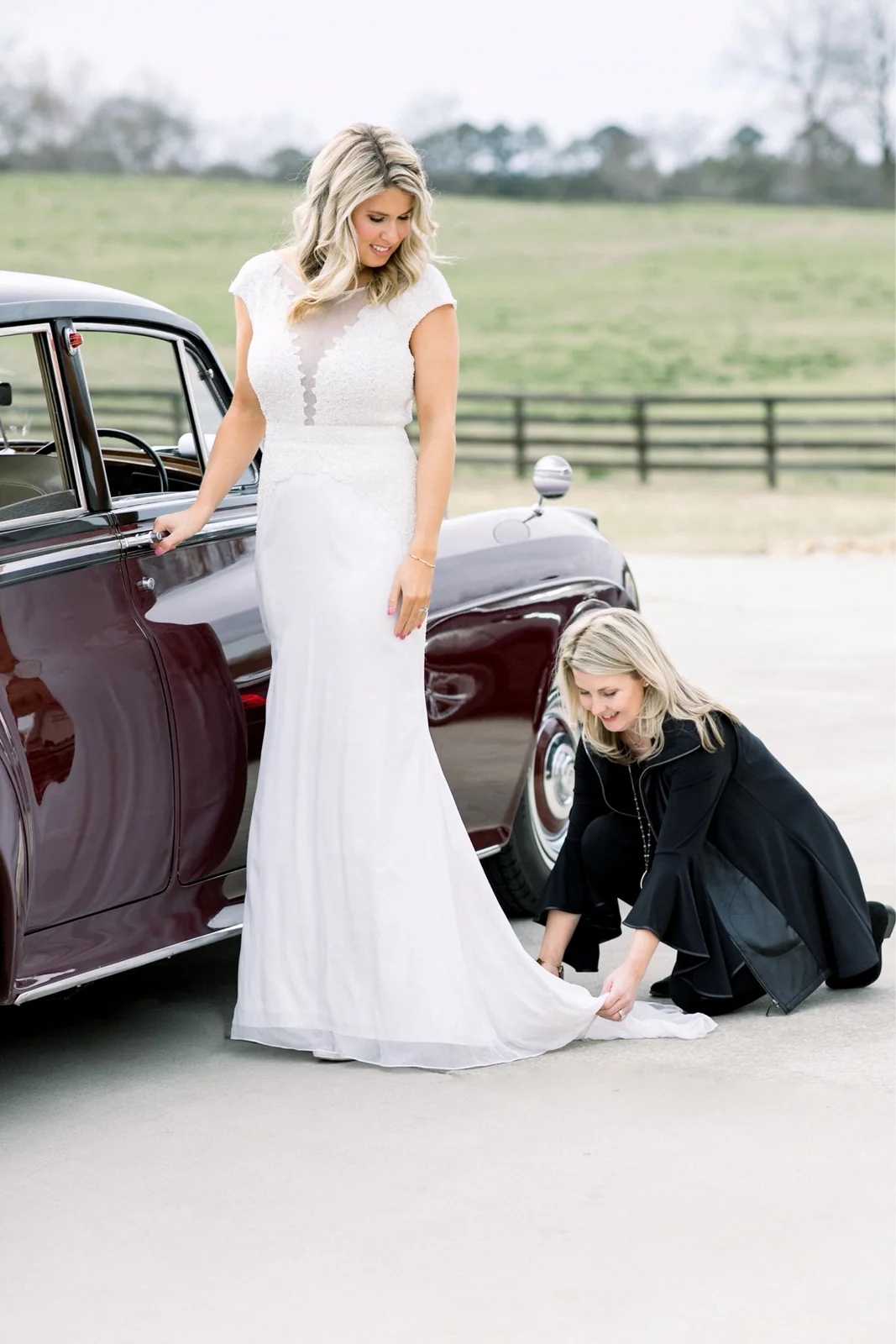Wedding professional kneeling beside a bride to help with final gown details